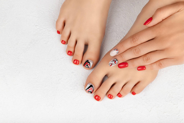 Womans voeten en handen op grijze achtergrond. Mooie zomer rode nagel ontwerp - Foto, afbeelding