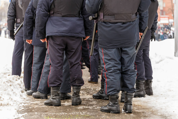ロシアの警察官の足で黒足首ブーツ、赤ストライプパンツとゴムtonfa夜スティック. - 写真・画像