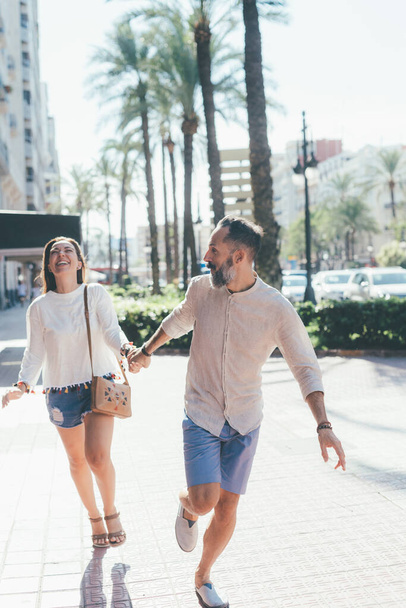 Adult couple running outdoor laughing hand in hand - Foto, imagen
