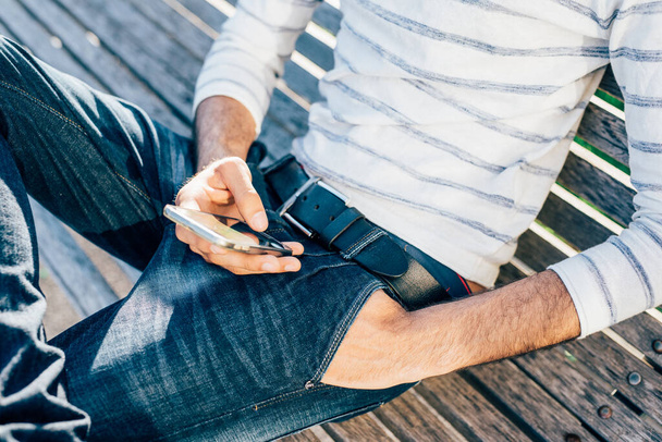 Primo piano mano uomo utilizzando smart phone panca seduta - Foto, immagini