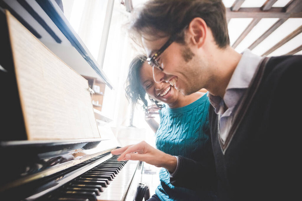 Multiethnic happy couple playing piano together at home - Photo, Image
