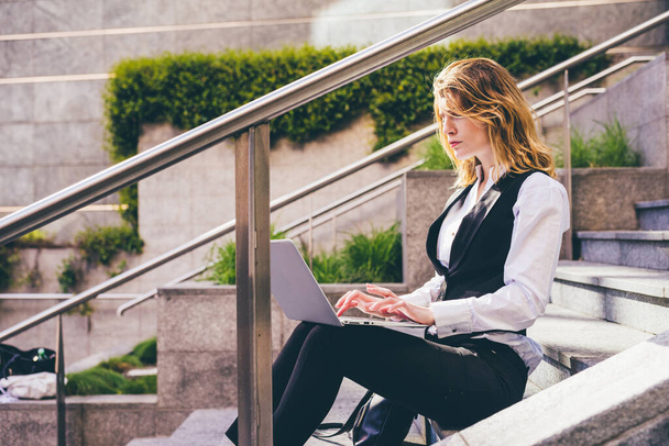 Young blonde cauciasian business woman working computer sitting outdoor - Foto, afbeelding