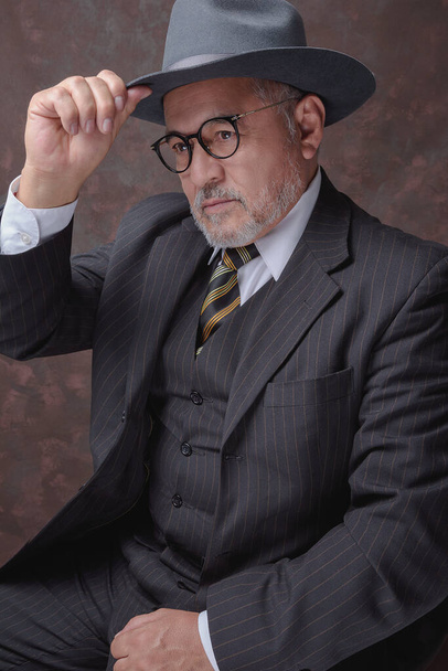 A mature gentleman posing for the camera in a dark brown pinstripe suit and hat - Φωτογραφία, εικόνα