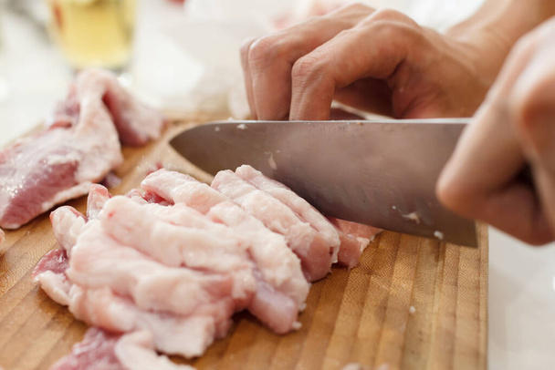 A man cook cuts pork meat with a knife. Cooking Concept - Foto, afbeelding