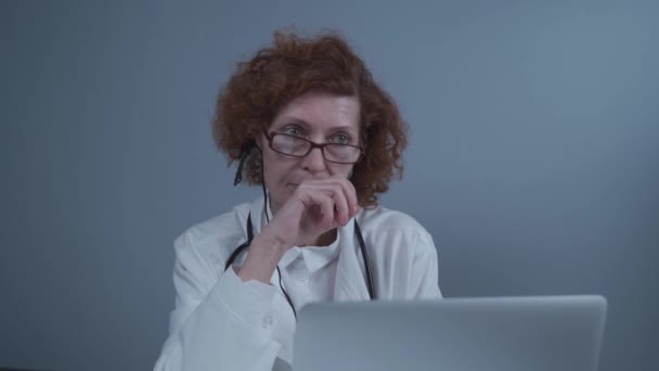 Gesundheitshelferin bei der Online-medizinischen Behandlung. Assistenzarzt trägt Kopfhörer-Video, das entfernte Patienten auf Laptop anruft. Telemedizinisches Konzept. Virtuelles Arzttermin-App online - Filmmaterial, Video