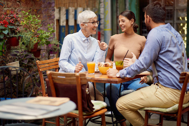 A group of friends of different generations talking while they have a drink in a relaxed atmosphere in the bar. Leisure, bar, friendship, outdoor - Fotoğraf, Görsel