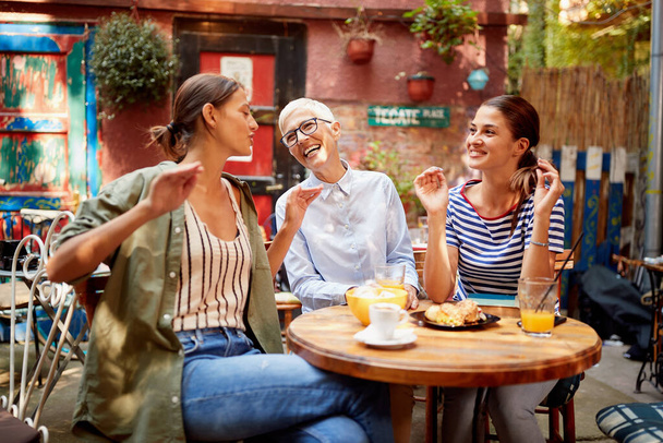 A group of female friends of different generations having a good time while they have a drink in a pleasant atmosphere in the bar. Leisure, bar, friendship, outdoor - Fotó, kép