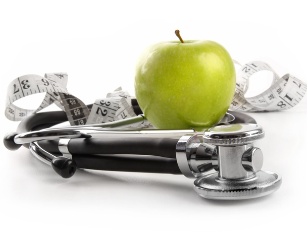 groene appel met stethoscoop op wit - Foto, afbeelding