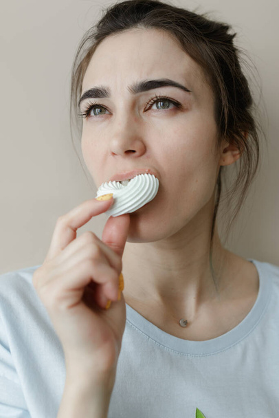 Young woman eating marshmallow. Pretty caucasian woman smiling. Sincere emotions. facial expressions - Foto, immagini