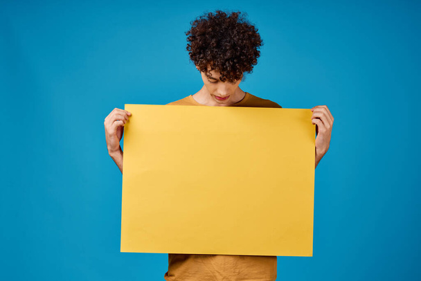 facet z żółtym plakatem w rękach Kopiuj przestrzeń reklama niebieskie tło - Zdjęcie, obraz