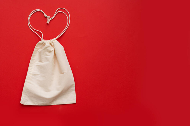 Vratná nákupní taška ve tvaru srdce na červeném pozadí. Bavlna nakupující na žlutém pozadí.Místo pro text. - Fotografie, Obrázek