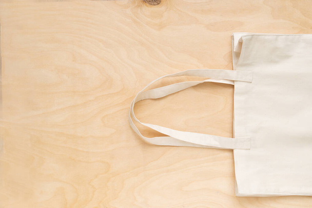 Mehrweg-Einkaufstasche auf Holzgrund. Baumwolleinkäufer auf grauem Hintergrund. - Foto, Bild