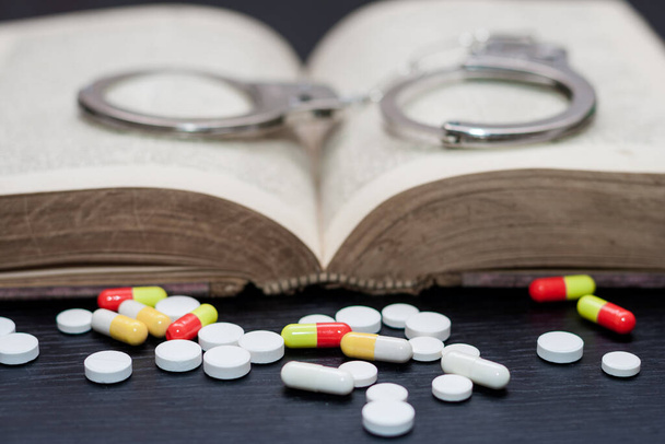 Handcuffs and pills and drugs on wooden table. Selective focus - Photo, Image