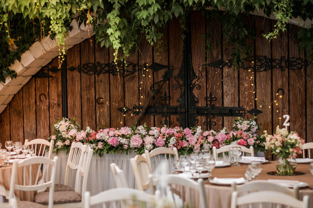 Egy esküvői fogadás főasztala gyönyörű virágokkal. Bazsarózsa esküvői dekoráció. - Fotó, kép