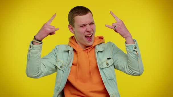 Overjoyed teen man showing rock n roll gesture by hands, cool sign, shouting yeah with crazy face - Footage, Video