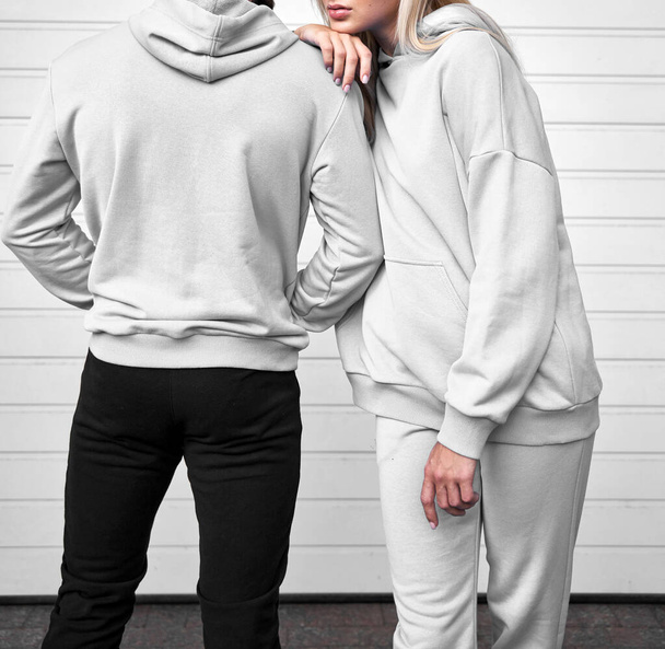 Kapucnis pulcsi egy lányon. Nő és férfi pár áll kapucnis pulcsiban. Branding és design mockup sablon. Textilszövet közelsége - Fotó, kép