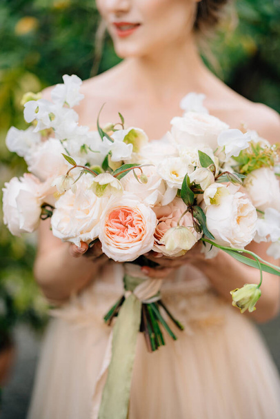 Невеста в красивом платье держит букет розовых цветов в руках - Фото, изображение