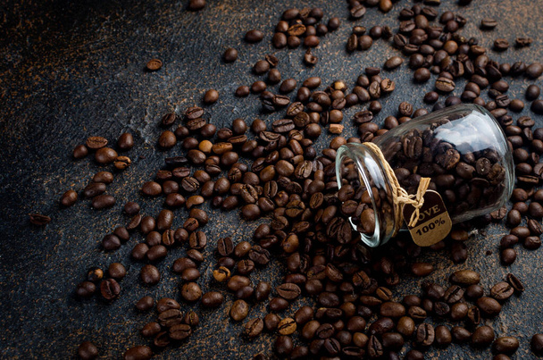 jar and sprinkled coffee beans  on dark concrete background. The concept of hot drinks, production or sale of coffee  - Foto, imagen