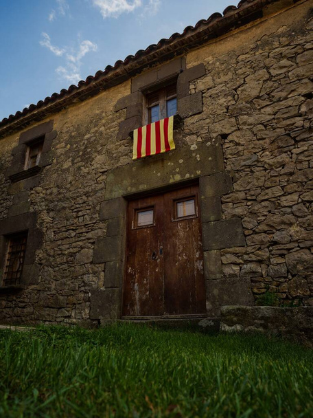 Középkori építészeti kő szikla épület Senyera zászló bájos furcsa történelmi óvárosi falu Tavertet Osona Collsacabra Katalónia Spanyolország Pireneusok Európa - Fotó, kép
