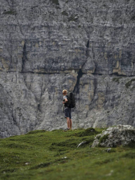 Молодой турист смотрит на массивную скальную стену вершины Tre Cime di Lavaredo в Sexten Dolomites Belluno, Южная Тироль Италия Альпы Европа - Фото, изображение