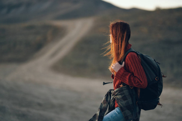 žena turista s batohem na zádech odpočívá v horách a silnici v dálce - Fotografie, Obrázek
