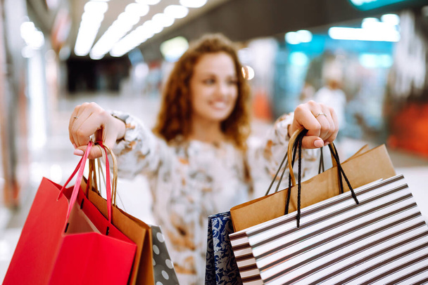 Shopping bags in the woman hands. Young woman with shopping bags walking in the mall. Spring shopping. Consumerism, sale, purchases,  lifestyle concept. - 写真・画像