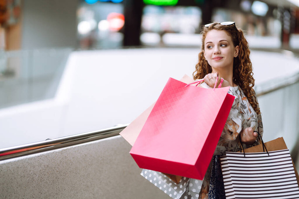Beautiful woman after shopping with shopping bags walks in the mall. Spring shopping. Purchases, black friday, discounts, sale concept. - Fotografie, Obrázek