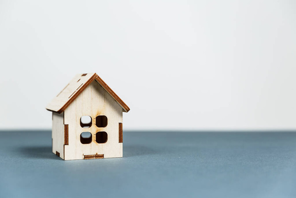 Концепция недвижимости. Маленький игрушечный деревянный дом с ключами на сером фоне с копировальным пространством - Фото, изображение