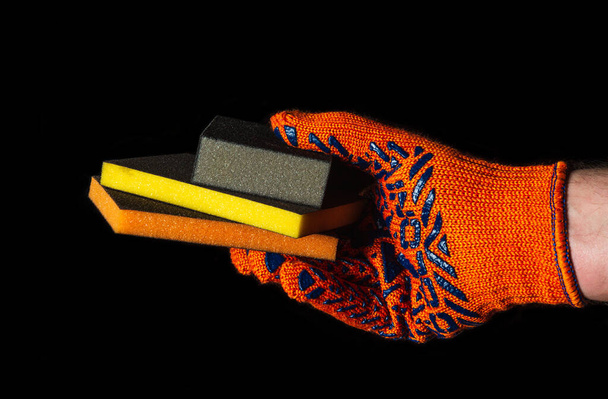 Bouwer hand in hand handschoen houdt of geeft schurende gereedschappen close-up op geïsoleerde zwarte achtergrond. Het idee om met een succesvol werk te beginnen. Gratis advertentieruimte - Foto, afbeelding