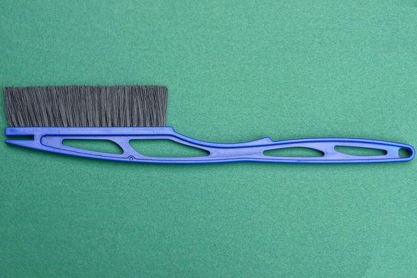 one blue plastic brush broom for cars with black bristles lies on a green table - Photo, Image
