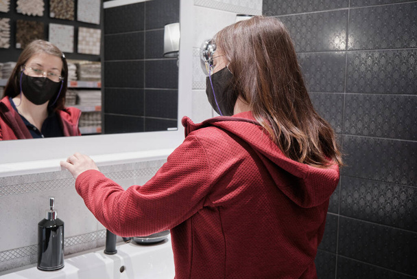 Женщина в маске против вируса в магазине. Она выбирает ванную комнату. - Фото, изображение