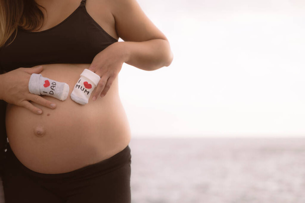 Soks με κείμενο στην κοιλιά της εγκυμοσύνης, φόντο εγκυμοσύνης, 9 μηνών κοιλιά της εγκυμοσύνης. - Φωτογραφία, εικόνα