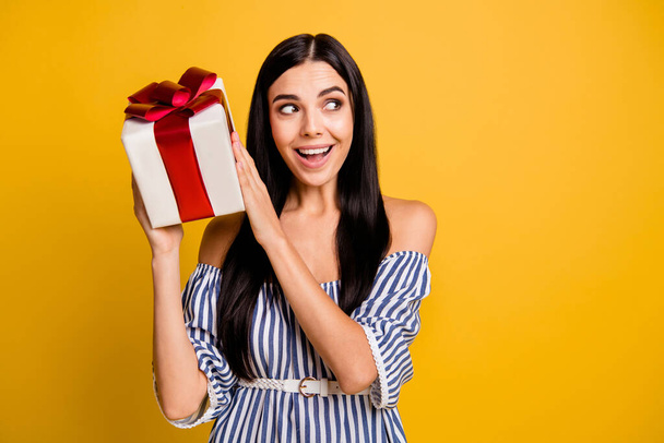 Photo of impressed young woman dressed off-shoulders dress curious present looking empty space isolated yellow color background - Photo, Image