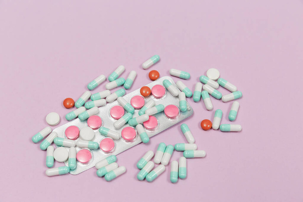 Erilaiset pillerit, kapselit ja tabletit läpipainopakkauksissa vaaleanpunaisella pohjalla ja tekstitila. - Valokuva, kuva