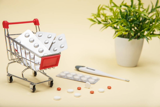Wózek sklepowy z tabletkami i lekarstwami. Tabletki w koszyku na niebieskim tle. Koncepcja: handel lekami, apteki. - Zdjęcie, obraz