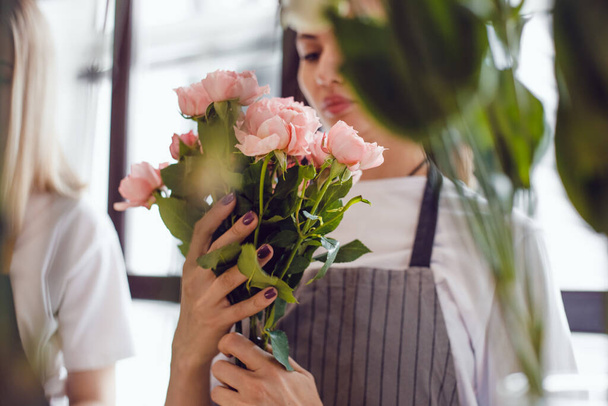 Young woman florist collects a bouquet of fresh roses. - 写真・画像