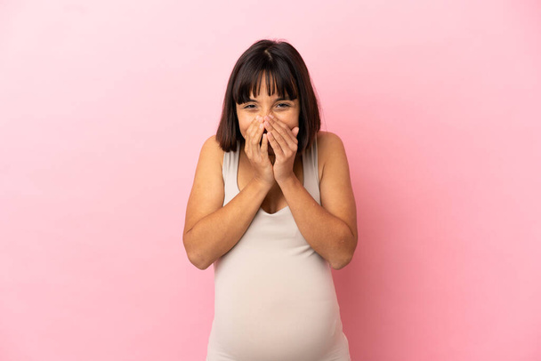 Jeune femme enceinte sur fond rose isolé bouche de couverture heureuse et souriante avec les mains - Photo, image