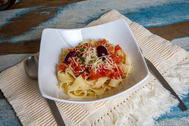 Fettuccine napoletana. Pasta con salsa de tomate casera fresca y perejil en un plato. Fondo de madera rústico colorido y mantel beige - Foto, Imagen