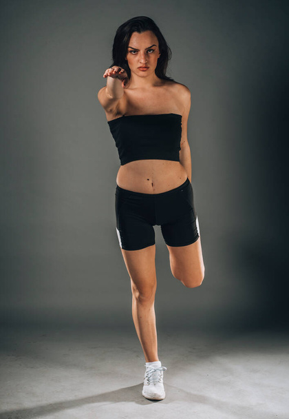 Jovem atraente caucasiano americano esportes fitness mulher em sportswear posando trabalhando isolado em fundo escuro no estúdio - Foto, Imagem