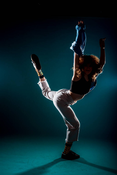 Caucasian female dancer exercising a contemporary dancing on cyan wall - Foto, Imagen