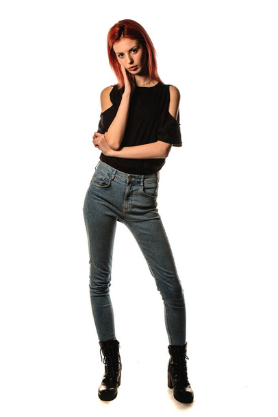 スタイリッシュなデニムパンツとブラックトップを身に着けている現代の女の子のスタジオファッションの肖像画 - 写真・画像