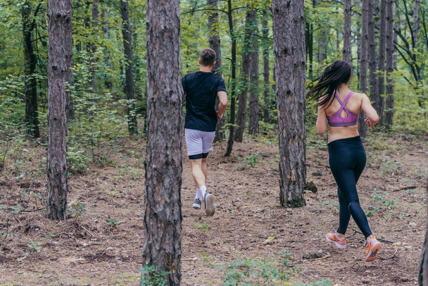Fit male and female athletes running in nature. Nature and sports concept. - Photo, Image