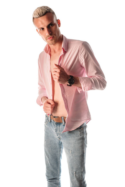 Trendy moderne jongeman gekleed in stijlvol rose goud shirt en blauwe denim broek - Foto, afbeelding