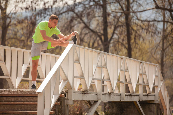 На мосту растягивается сильный спортсмен - Фото, изображение