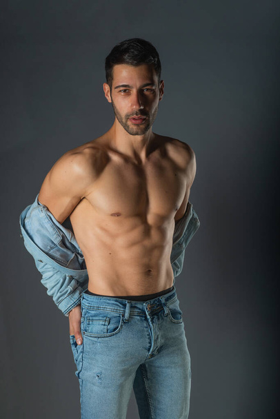 Handsome muscular shirtless young man standing confident, profile view, looking at camera - Photo, Image