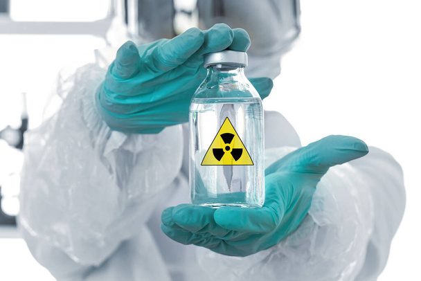 Osoba v chemické ochraně prokazující lahvičku čiré kapaliny. Falešné označení Nebezpečí nebo varovné symboly  - Fotografie, Obrázek