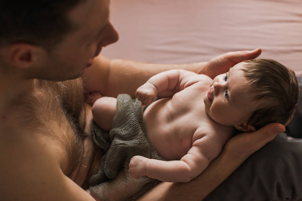 Naked father holding a naked tiny baby in his arms. 3 months. Indoor. - Foto, Imagem