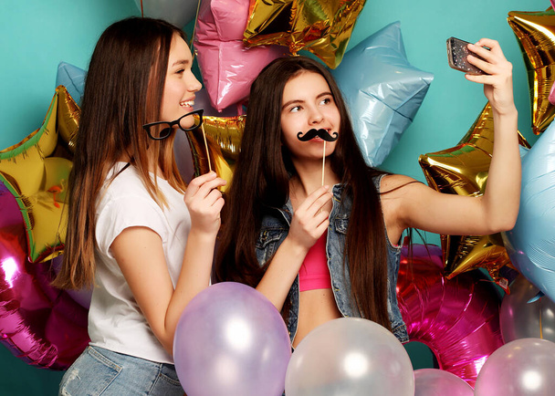 Two girls friends with colorfoul balloons make selfie on a ph - Foto, Imagen