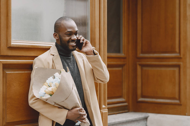 African man with bouquet of flowers waiting for girlfriend - Foto, afbeelding