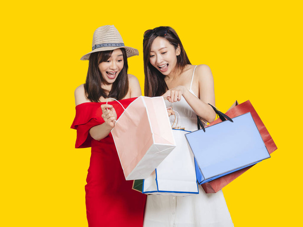 happy young women looking into shopping bags - 写真・画像